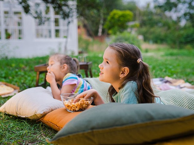 Dos niñas en colchonetas y cojines en el jardín de su casa