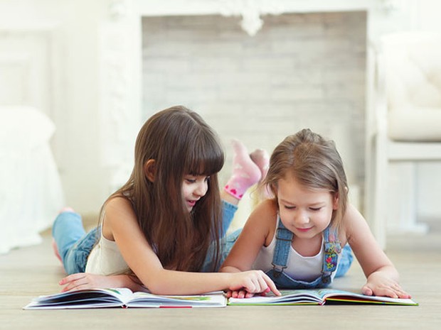 Dos niñas tumbadas en el suelo leyendo libros