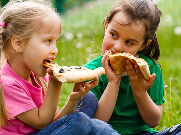 Dos niñas comiendo pizza en un parque