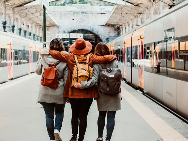 Tres amigos de espaldas en una estación de tren