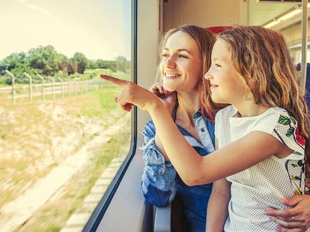 Niña y su madre mirando por la ventana de un tren