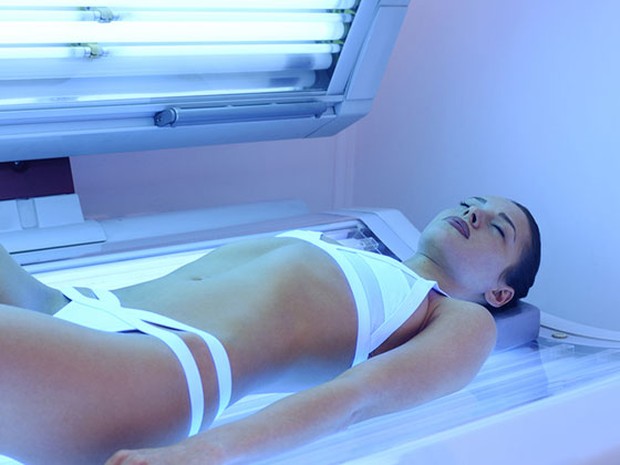 Mujer joven con un bikini blanco tumbada en una cama de rayos uva