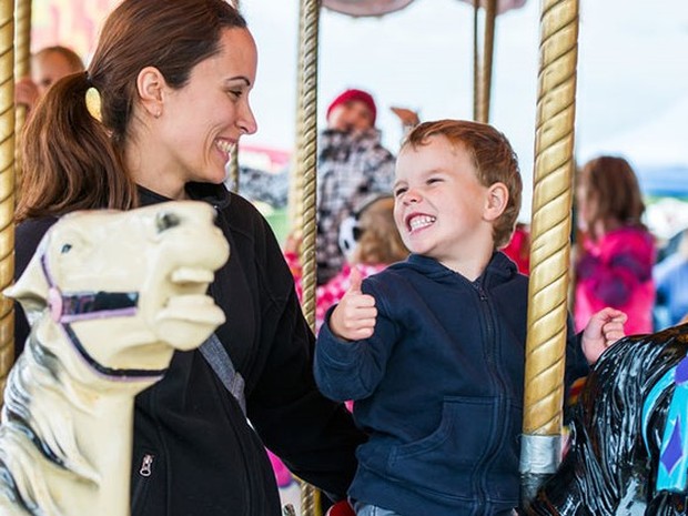 Madre e hijo muy sonrientes montados en un tiovivo
