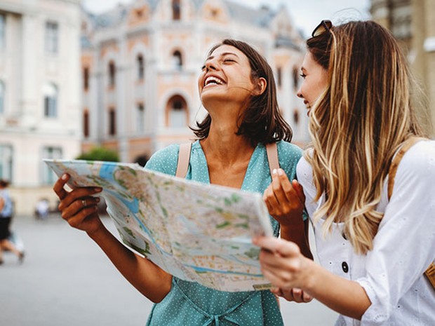 Dos mujeres riéndose y haciendo turismo con un mapa