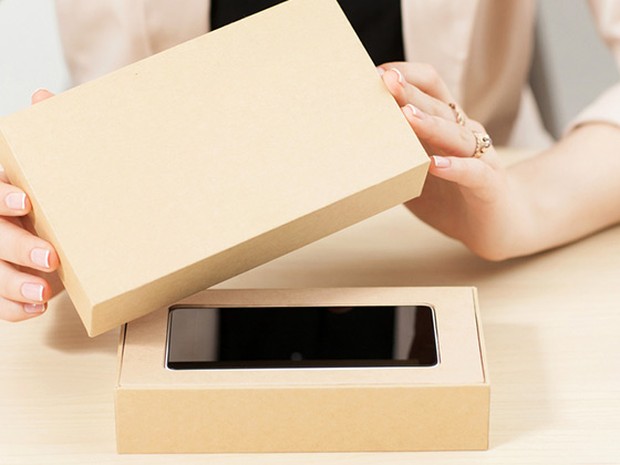 Mujer destapando una caja beige con un smartphone nuevo dentro