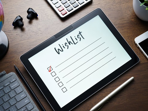 tablet con una wishlist, auriculares, teclado, calcuradora y smartphone alrededor