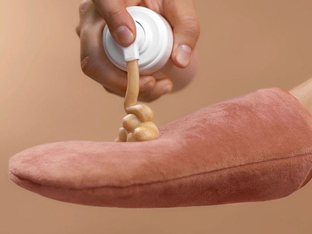 Mano echando autobronceador en un guante de bronceado de color salmón