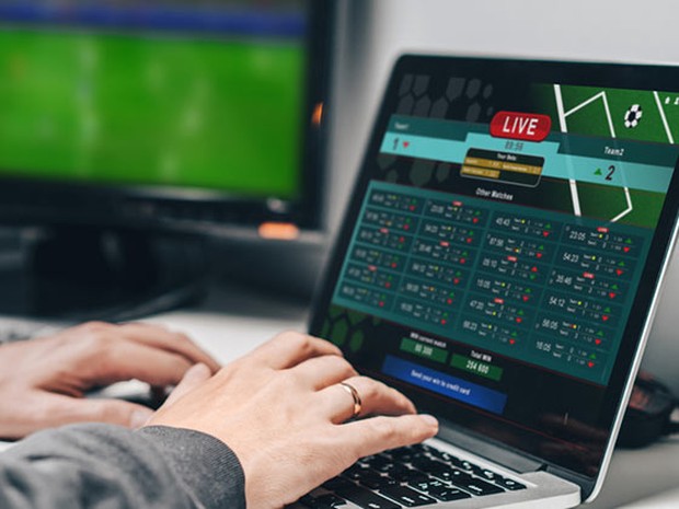 Persona viendo contenido de fútbol online con una tele de fondo