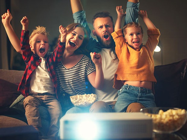 Una familia frente a un proyector disfrutando de una película con palomitas