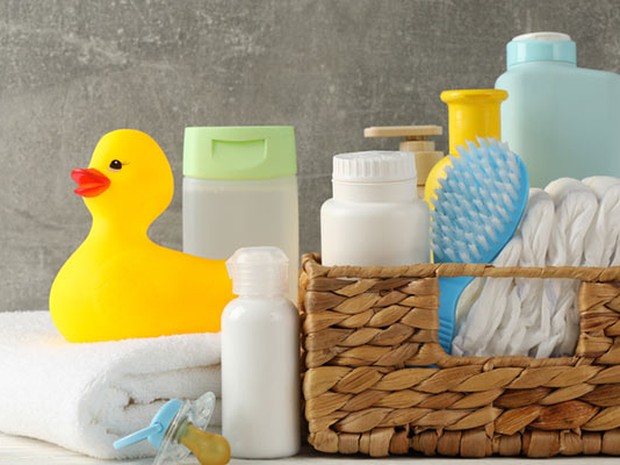 Cesta de mimbre que contiene productos de higuiene para bebés junto a un patito de goma