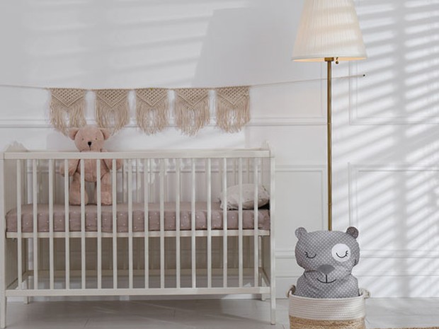 Cuna infantil junto a una lámpara y un oso de peluche