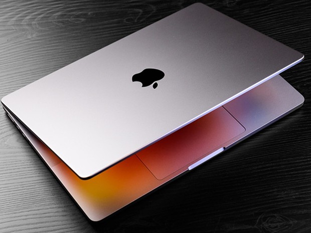 Ordenador portátil Mac semi abierto sobre una mesa de madera oscura