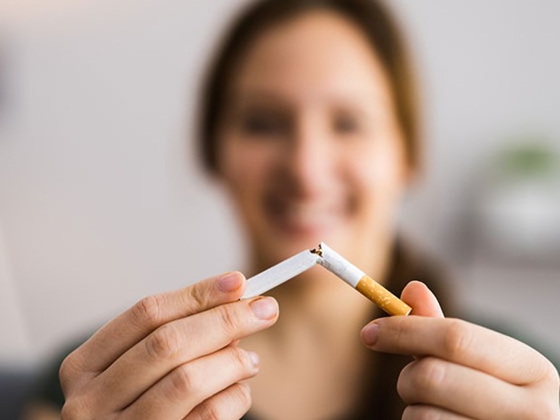 Chica joven en segundo plano (difuminada) rompiendo un cigarrillo por la mitad