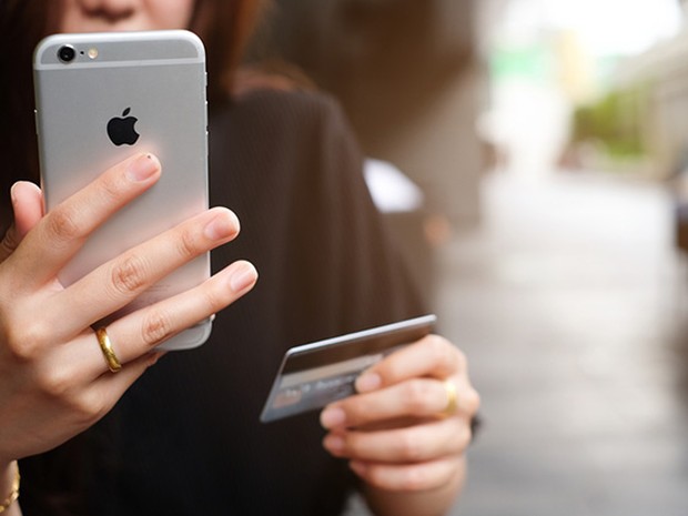 Mujer con un iPhone y una tarjeta de crédito