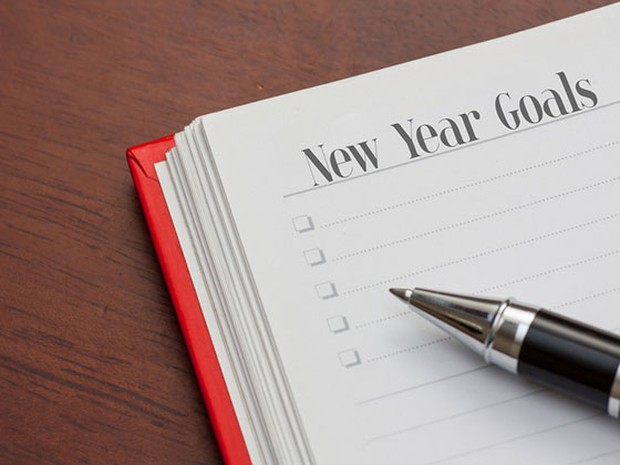 Cuaderno con New Year Goals sobre una mesa de madera y con un bolígrafo negro encima