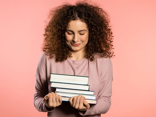 Chica jóven con varios libros entre sus brazos