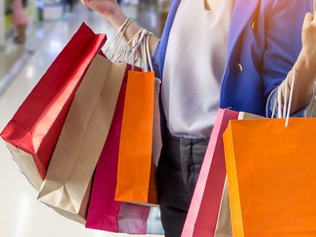 Mujer con varias bolsas de compras de colores en los brazos