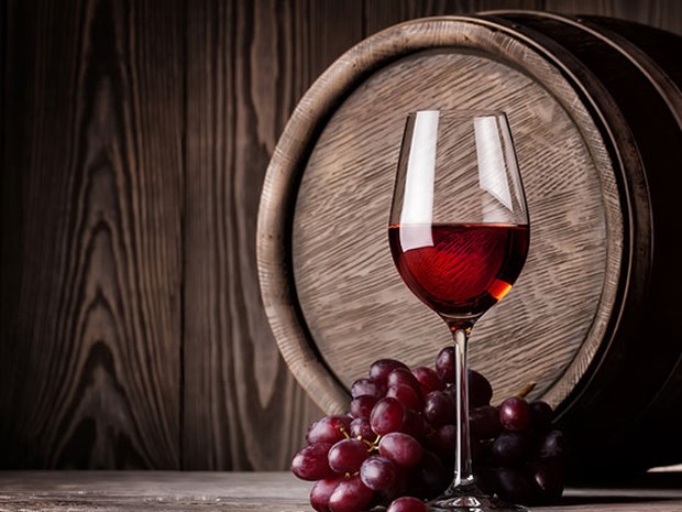 tonel de vino, copa de vino tinto y uvas rojas