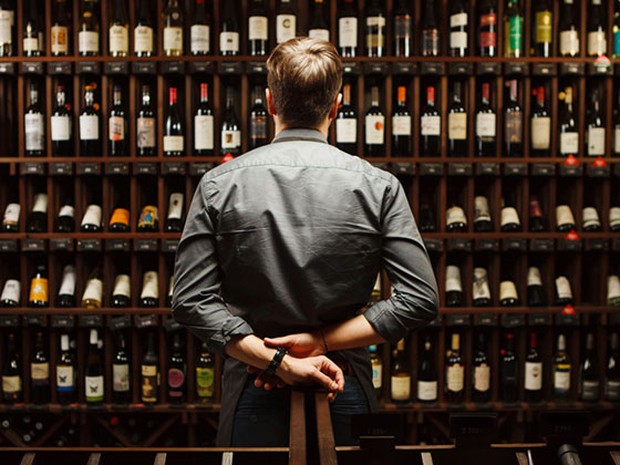 hombre mirando una estantería llena de botellas de vino