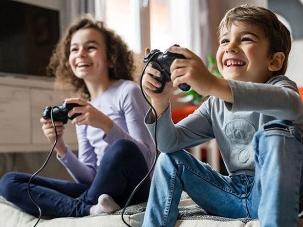 Dos niños riendo y jugando con una consola
