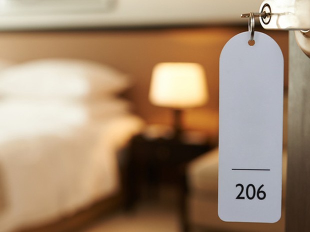 Llave de un hotel sobre la cerradura de una puerta abierta donde se ve la habitación