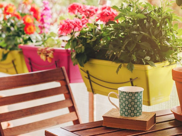 Macetas con flores junto a una mesa y silla de un balcón