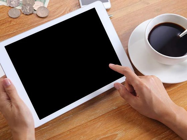 persona usando una tablet y tomando café