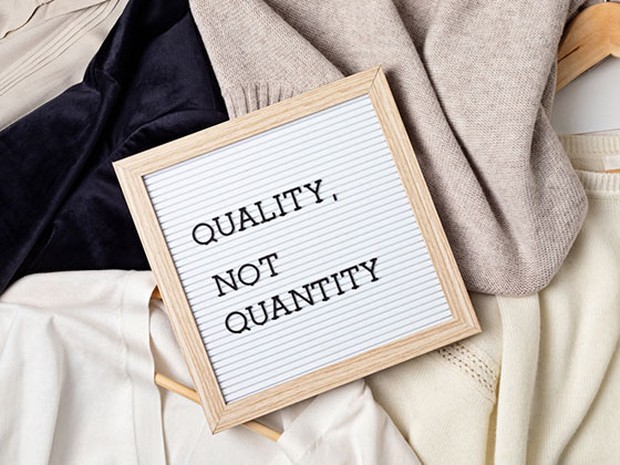 Cartel con la frase "quality not quantity" sobre un fondo de ropa