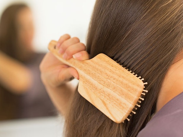 Mujer de espaldas frente a un espejo cepillándose el cabello