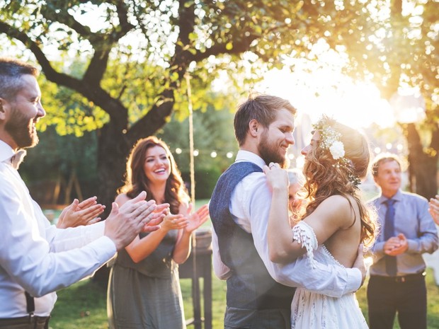 Una pareja de recién casados bailando en su boda con los invitados aplaudiendo