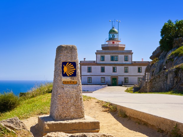Hito de Finisterra indicando el final del Camino, de fondo se ve el faro