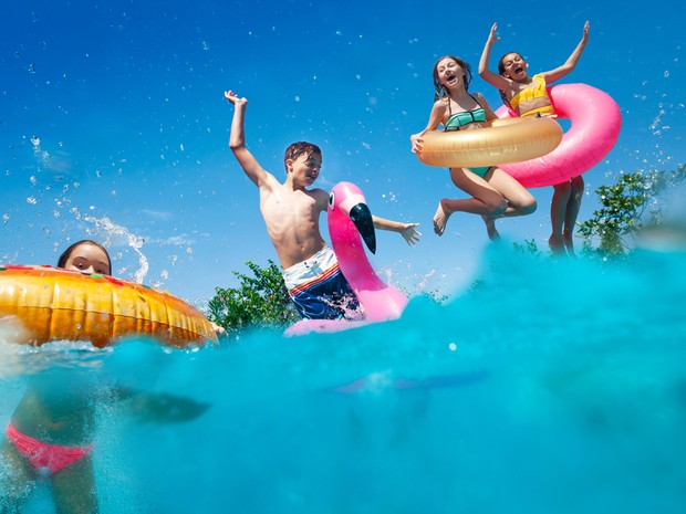 Niños con flotadores tirándose a la piscina