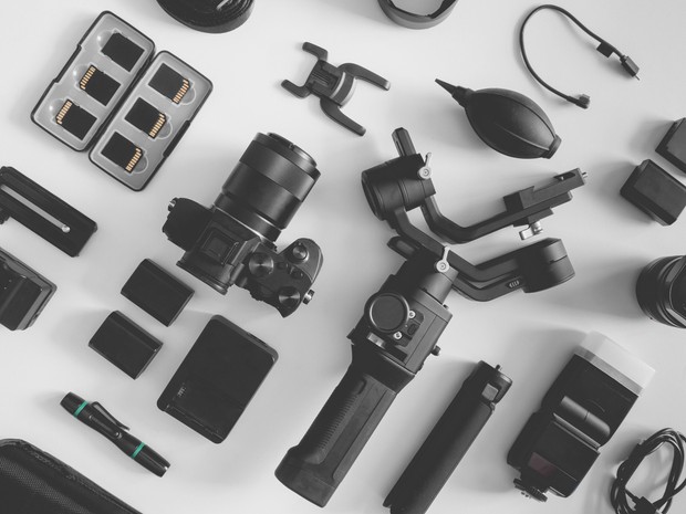 Vista superior de un fondo blanco con una cámara réflex, tarjetas SD, estabilizadores Gimbal y otros accesorios de cámara