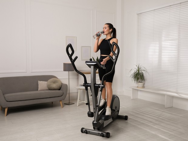 Chica con una bicicleta elíptica en su salón