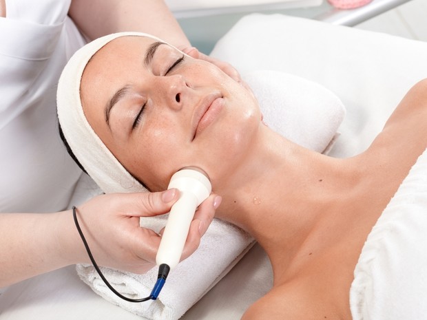 Mujer joven haciéndose un tratamiento de belleza tumbada en una camilla blanca