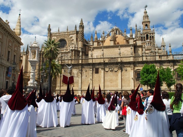 Procesión de Semana Santa en andalucía con nazarenos con capuchones granates y túnicas blancas