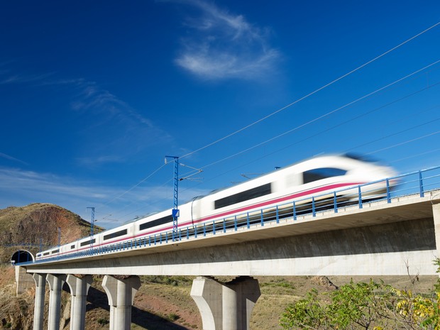 Tren AVE en movimiento saliendo de un túnel con un cielo azul espléndido