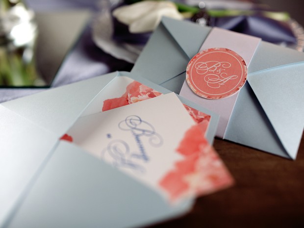 Invitaciones de boda con el sobre azul y un faldón blanco con un sello rosa. Uno de los sobres está abierto y asoma la invitación