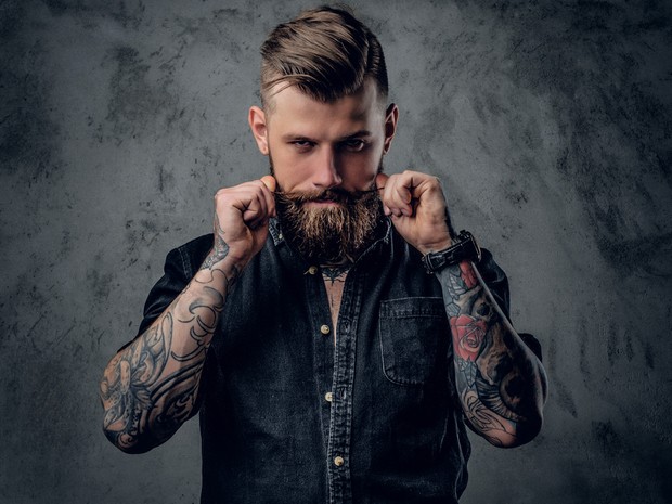Hombre hipster tocándose el bigote perfilado hacia arriba