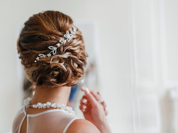 Mujer de espaldas con un recogido con decoraciones brillantes, muy estilo boda. Lleva puesto lo que parece ser un vestido de novia.