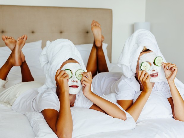 Dos chicas con pepino en los hojos y mascarilla en la cara
