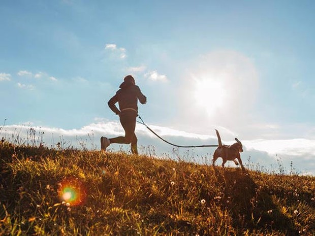 Chico haciendo running con un perro por el campo